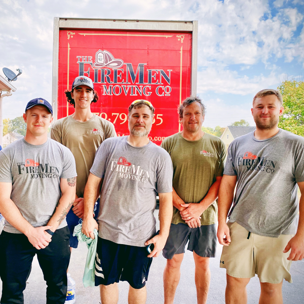 Team of sweaty movers standing in front of a moving truck