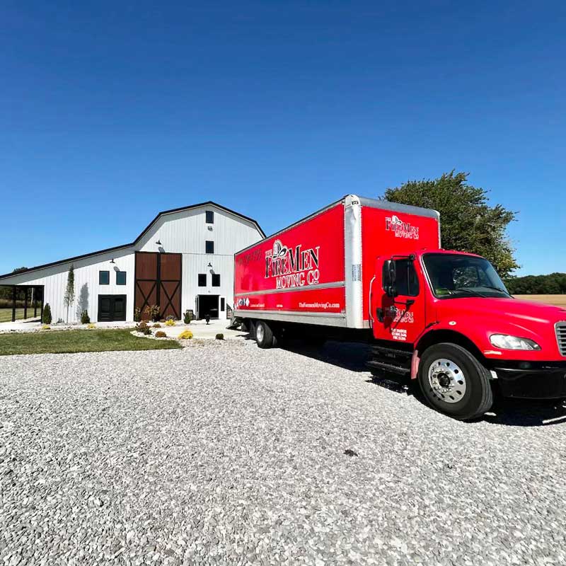 red moving truck parked on a gravel lot