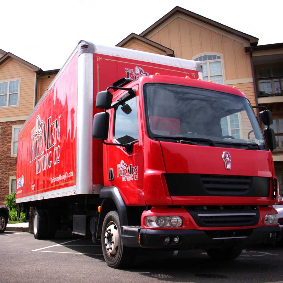red moving truck parked in front of an apartment complex