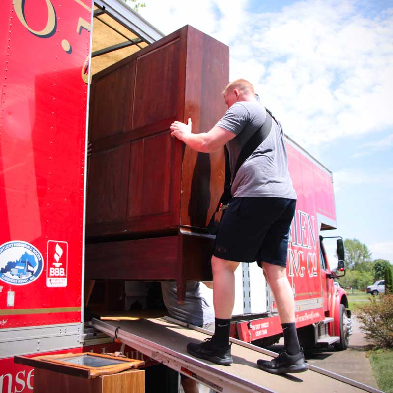 Mover loading a large cabinet into a moving truck