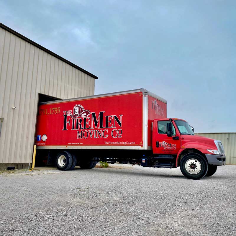 Medium sized red moving truck backed into a storage warehouse