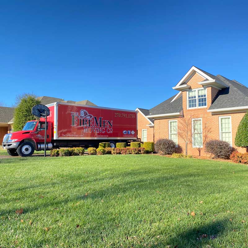 large red moving truck parked in the driveway of a suburban home