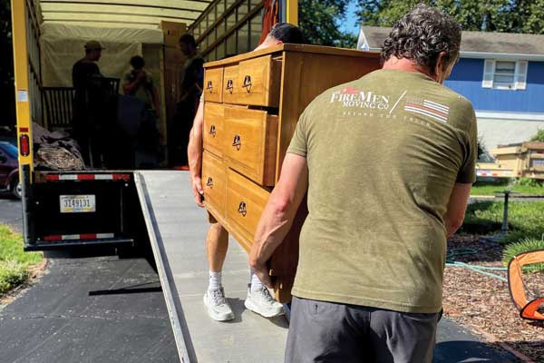 Two movers lifting a dressing into a moving truck