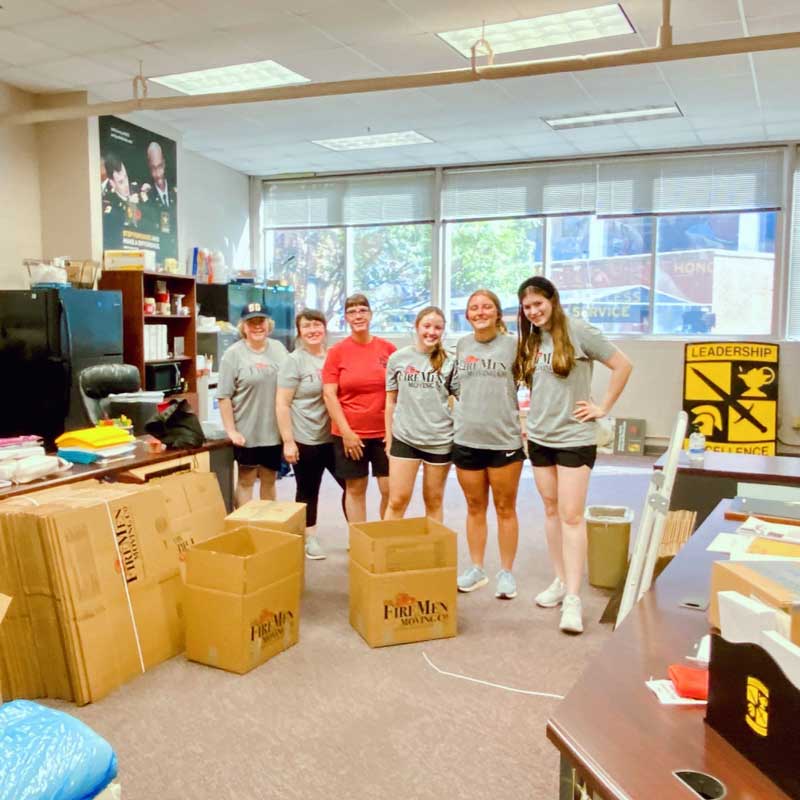 women standing in an office packing supplies into boxes