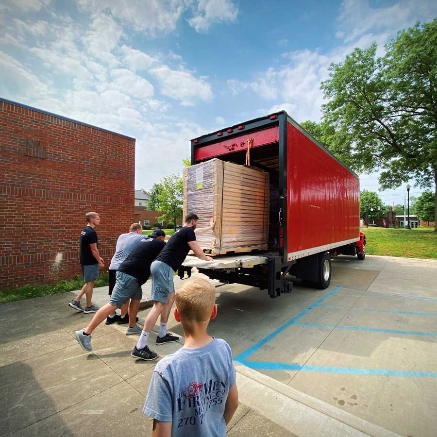 movers load a full pallet into the back of a red moving truck