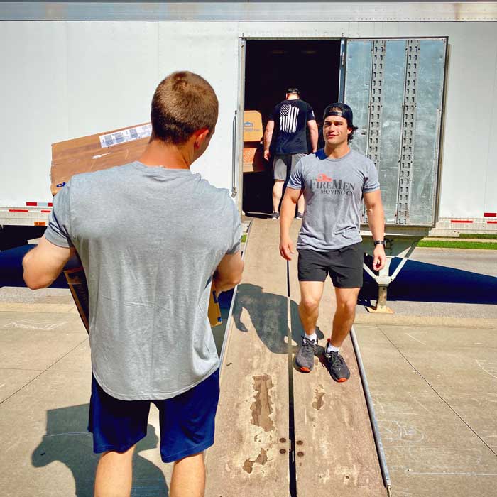 Two movers passing by each other as they load a moving truck