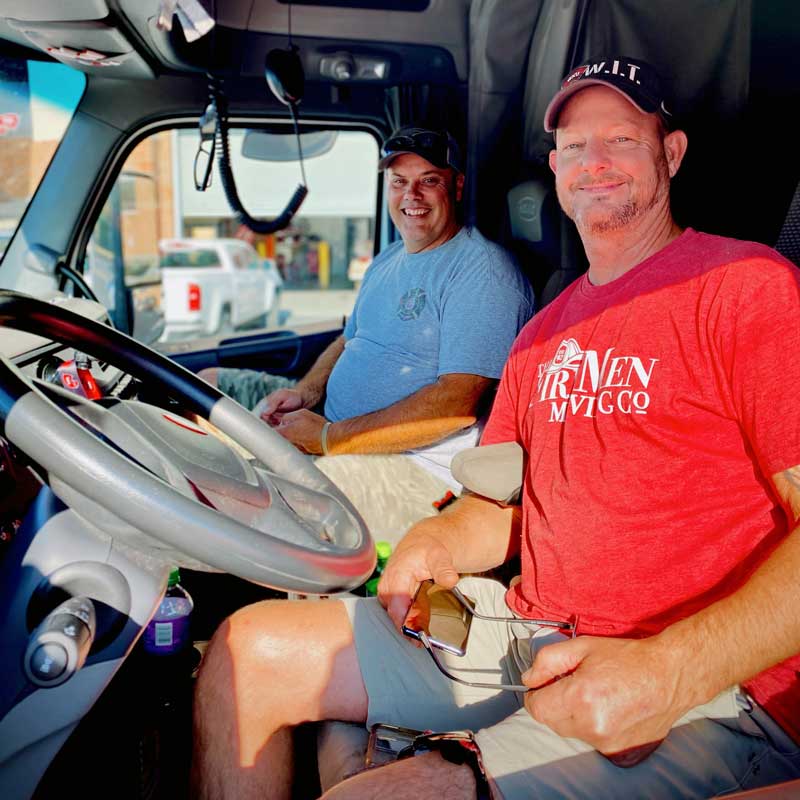 Two movers smiling, sitting in a semi-truck